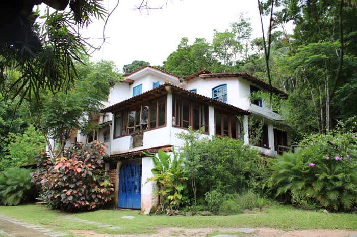 Casa-sede colonial da fazenda, com porta azul e jardim florido