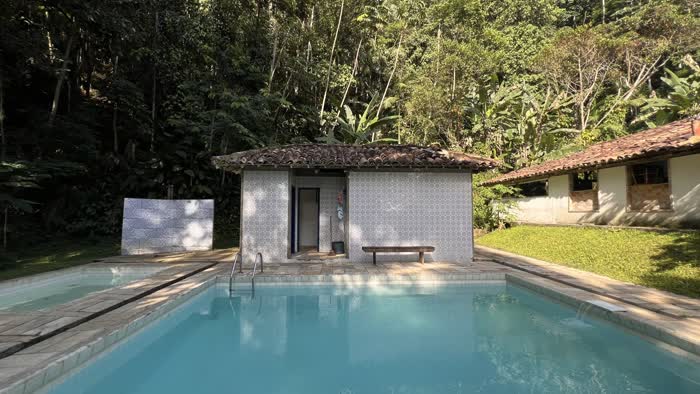 Piscina da fazenda com o vestiário colonial de telhado de barro ao fundo